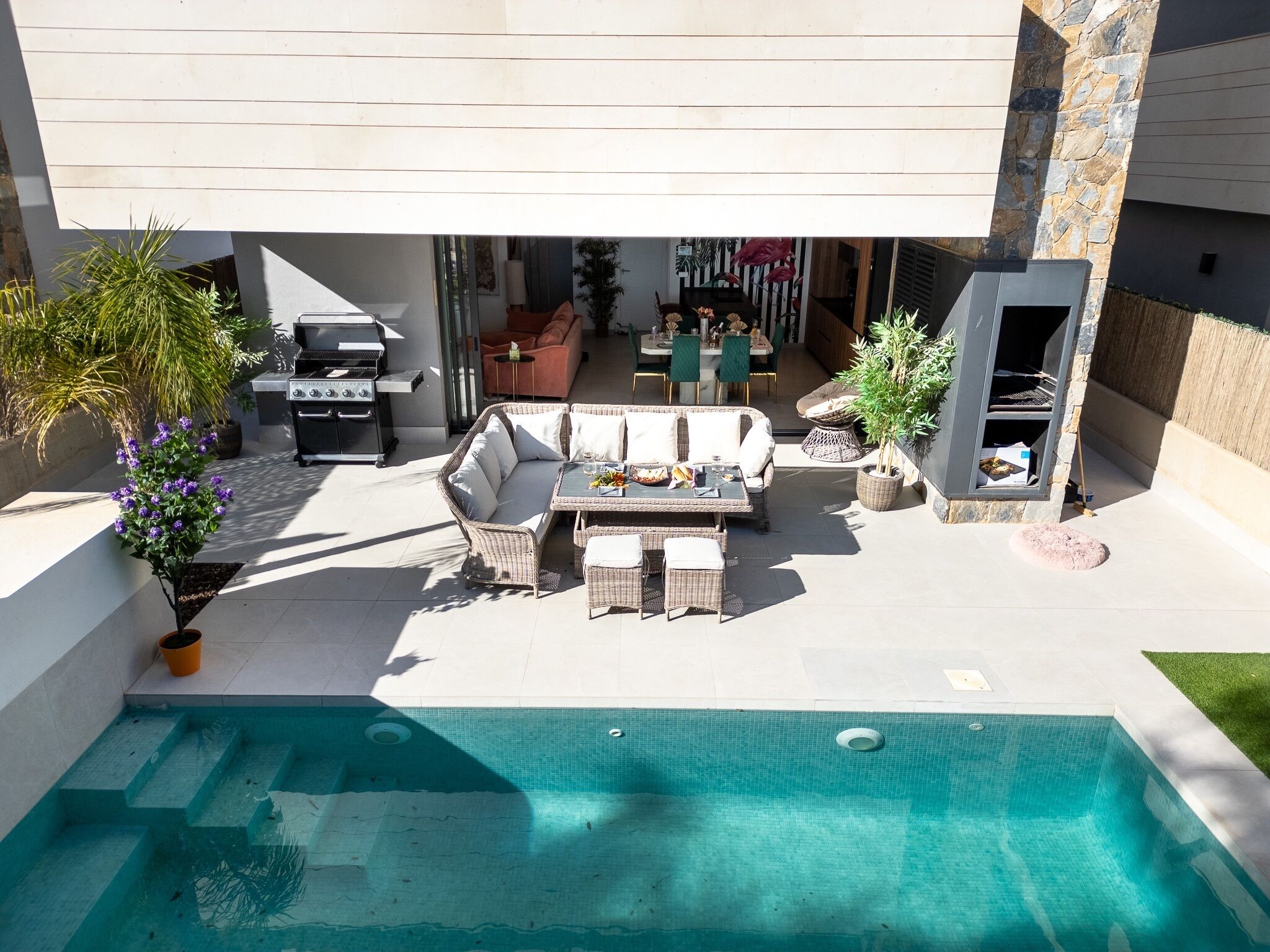 A modern outdoor living area with a pool, seating, and a barbecue.