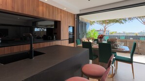 A modern kitchen with a built-in stove, a sink, and a dining area with a table and chairs.