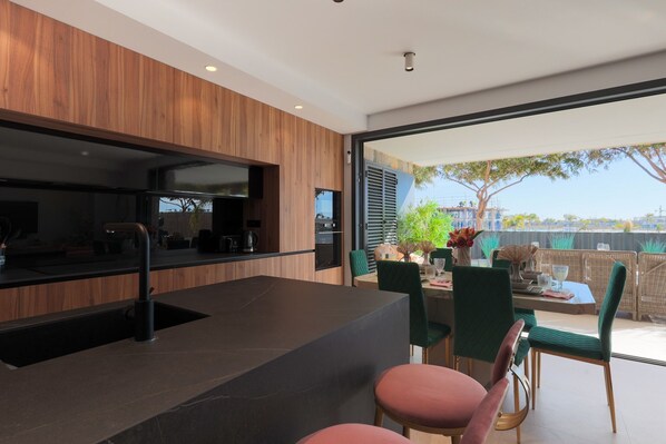 A modern kitchen with a built-in stove, a sink, and a dining area with a table and chairs.