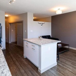 Modern kitchen with a central island, white cabinetry, and a stainless steel sink.