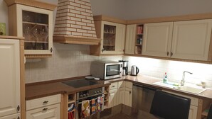 A kitchen with white cabinets, a microwave, a stove, and a sink. - Vacation home with summer pool and garage, free of stairs/steps (Jesewitz)