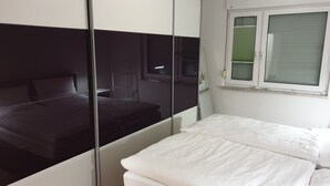 A bedroom with a bed, a wardrobe, and a window. - Vacation home with summer pool and garage, free of stairs/steps (Jesewitz)