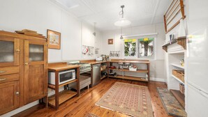 A compact kitchen with wooden cabinetry, a stove, microwave, and a sink. - Ferntree Cottage in Blackheath (Blackheath)