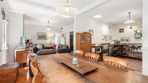 A spacious living area with a wooden dining table, leather sofas, and a kitchen with modern appliances. - Ferntree Cottage in Blackheath (Blackheath)