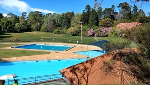 A swimming pool with two sections, surrounded by a grassy area and trees. - Ferntree Cottage in Blackheath (Blackheath)
