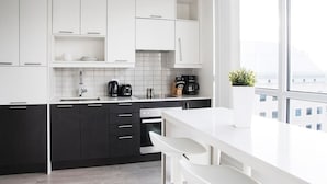 A modern kitchen with white and dark cabinets, a white countertop, and a window with a city view.
