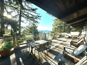 A wooden deck with a table and chairs, overlooking a forested area and a body of water. - Paradise in Forest setting w/ Ocean views, hot tub, close to town & Hiking (Eastsound)