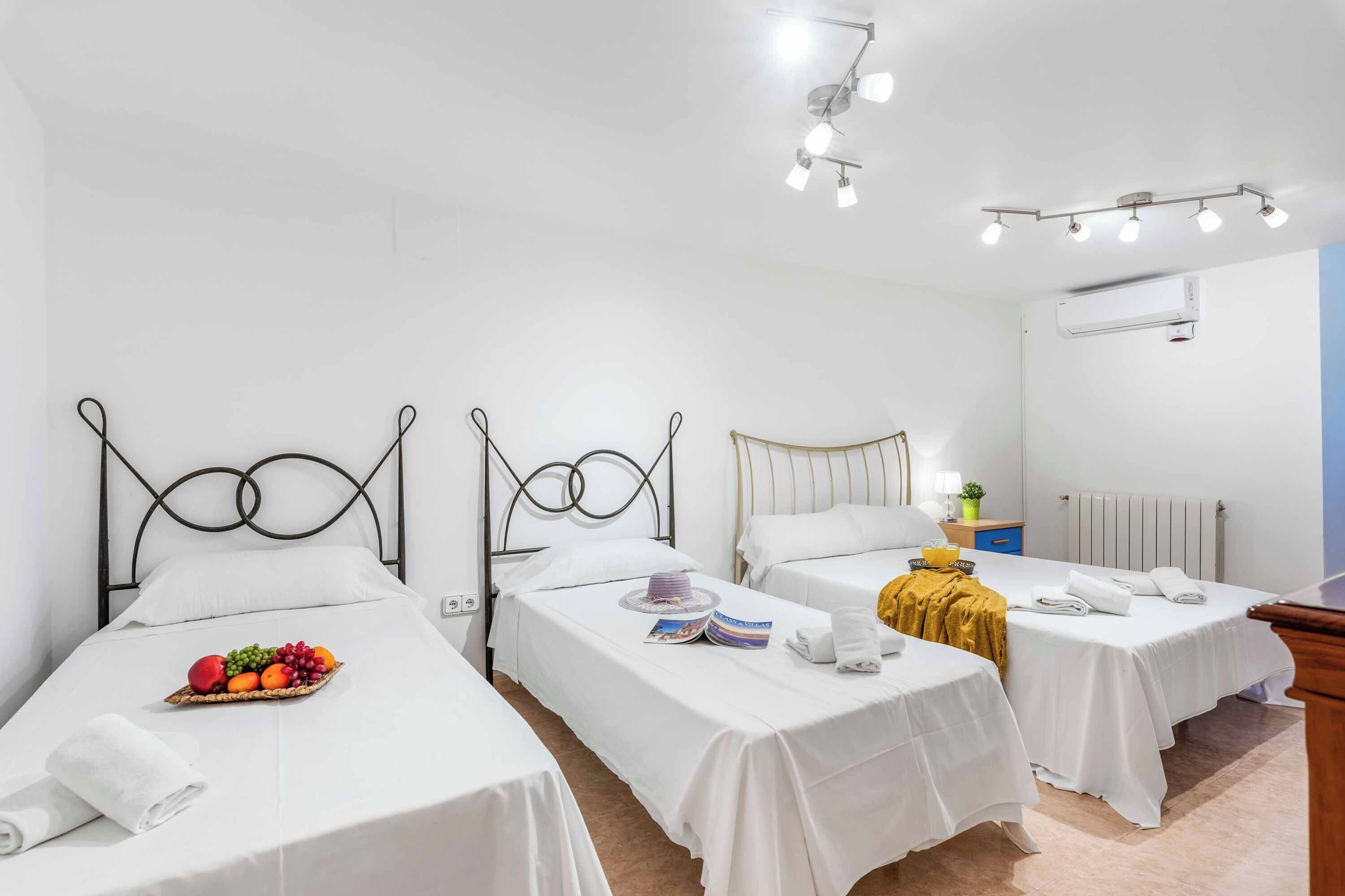 Ein Hotelzimmer mit zwei Einzelbetten, einem kleinen Tisch mit Obstkorb, einem Nachttisch mit Buch und Tasse sowie einem Heizkörper an der Wand.