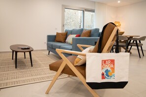 A living room with a sofa, a chair, a small table, and a rug. - Lar da Onda - By SCH (Nazaré)