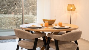 A round dining table with two chairs, a bowl of fruit, two glasses of orange juice, and a lamp. - Lar da Onda - By SCH (Nazaré)