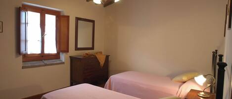 A bedroom with two beds, a dresser, a window with curtains, and a ceiling light fixture.