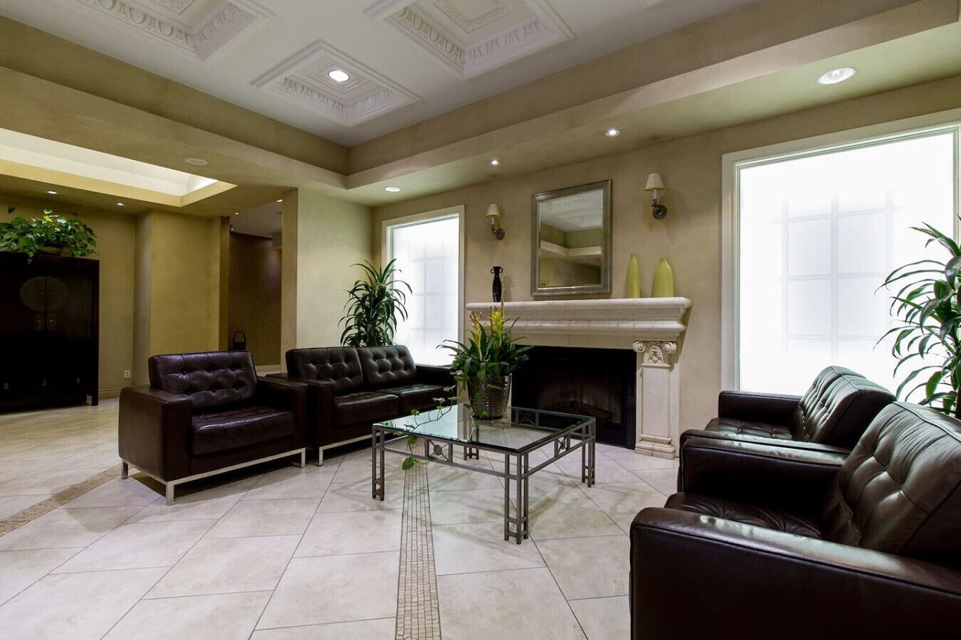 A spacious living room with leather sofas, a glass coffee table, and a fireplace.