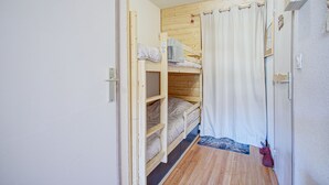 A small, compact room with a bunk bed, a wooden door, and a curtain. - Le Petit Montagnard - Station accessible à pied (Les Angles)