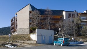 A multi-story building with a modern architectural design, featuring a mix of stone and wood materials. - Le Petit Montagnard - Station accessible à pied (Les Angles)