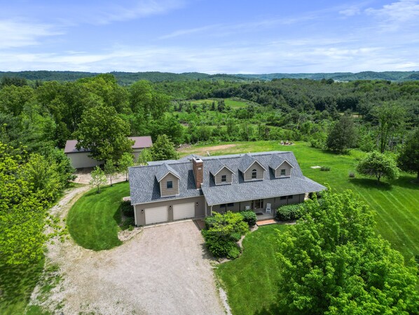 A large, two-story house with a spacious front yard and a driveway leading to a garage.