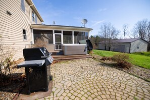 A backyard with a grill, a hot tub, and a shed.