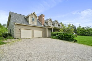 A two-story house with a garage, a chimney, and a gravel driveway.