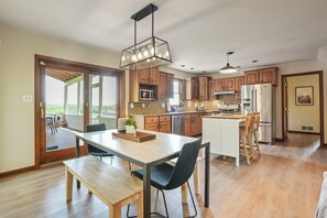 A modern kitchen with wooden cabinets, a central island, and a dining area with a bench and chairs.