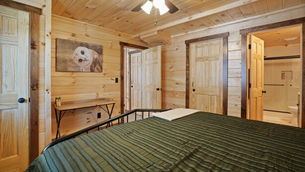 Ein Zimmer mit Holzwänden, einem Bett, einem Deckenventilator und einem Gemälde einer Eule.