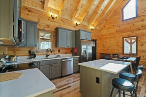 A modern kitchen with wooden walls, stainless steel appliances, and a central island with bar stools.