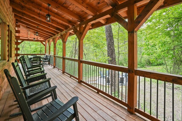 A covered wooden deck with benches, surrounded by trees.