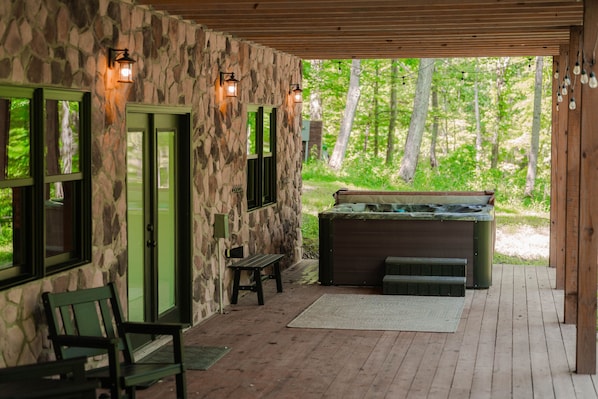 A stone building with a hot tub, wooden deck, and benches.