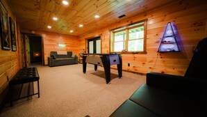 Un interior de madera con una mesa de billar, un sofá y una mesa de futbolín.