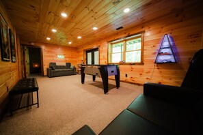A wooden interior with a pool table, a sofa, and a billiards table.
