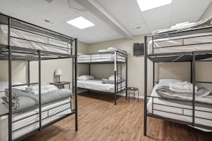 A dormitory room with bunk beds, a small table with a lamp, and a ceiling light.