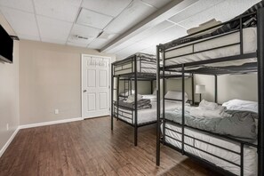 A dormitory room with bunk beds, a door, and a wooden floor.
