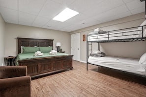 A room with a wooden bed, a bunk bed, a bedside table, a lamp, and a chair. - Deer Ridge Lodge | Hocking Hills, Sleeps 26, Pool (Laurelville)