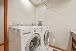 A laundry room with two white LG Direct Drive washing machines, a wooden floor, and a white ceiling. - Deer Ridge Lodge | Hocking Hills, Sleeps 26, Pool (Laurelville)