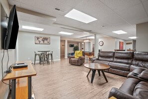 A spacious living area with a wooden coffee table, leather sofa, and a flat-screen TV mounted on the wall.