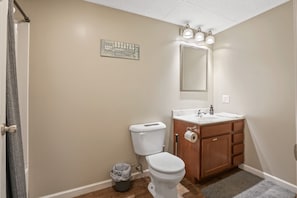 A bathroom with a toilet, sink, vanity, and a mirror.