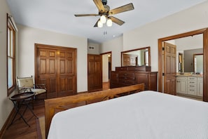 Une chambre à coucher avec un grand lit, une armoire en bois et un ventilateur de plafond.