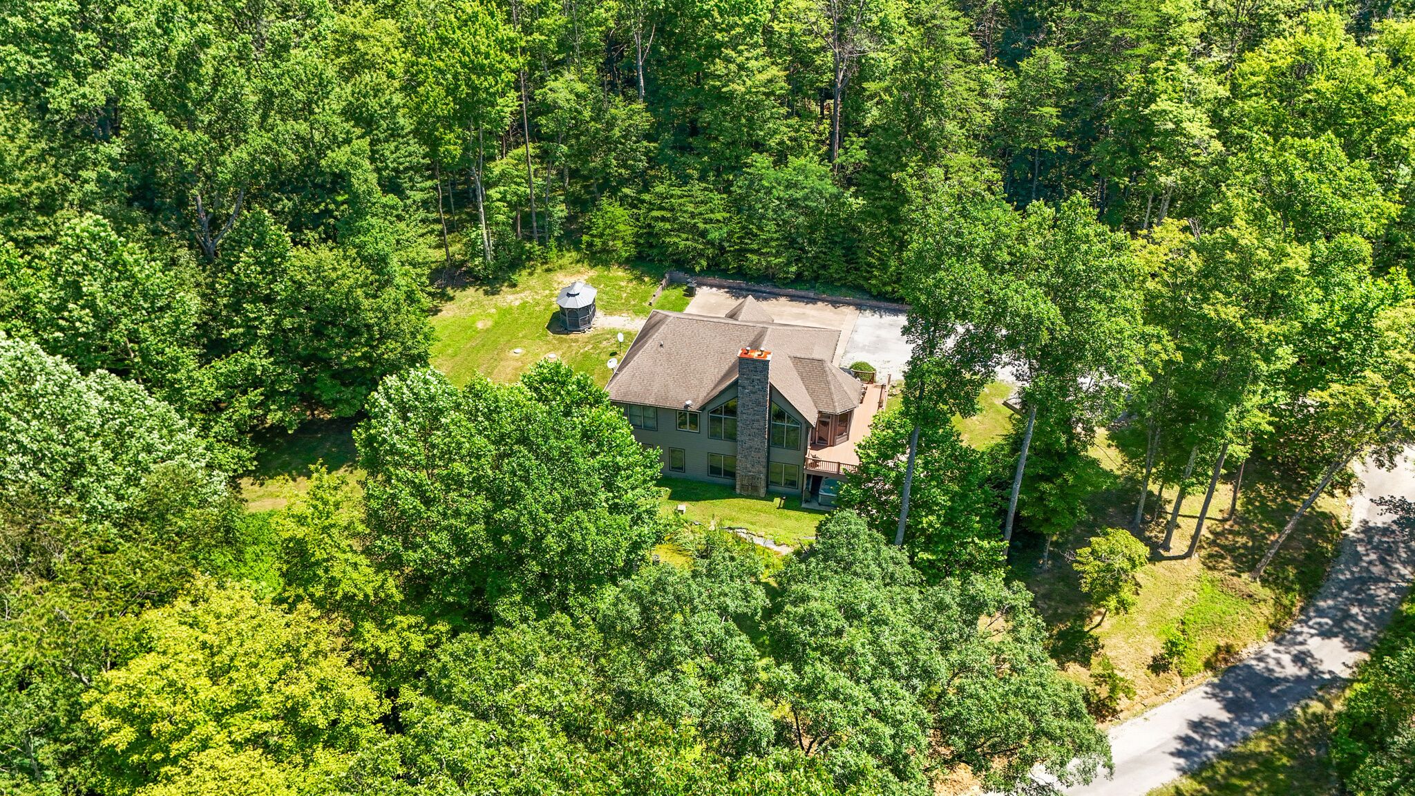 A large, single-story house surrounded by dense forest.