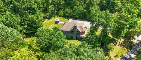 A large, single-story house surrounded by dense forest.