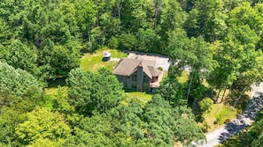 Une grande maison de plain-pied, entourée d’une forêt dense.