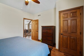 Ein Schlafzimmer mit Bett, Holzschrank und Tür.