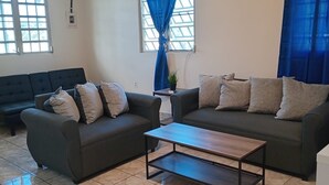Ein Wohnzimmer mit zwei dunklen Sofas, einem Holztisch und einem Fliesenboden.