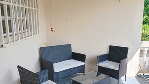 Ein überdachter Außenbereich mit Korbmöbeln und einem Betonboden.
