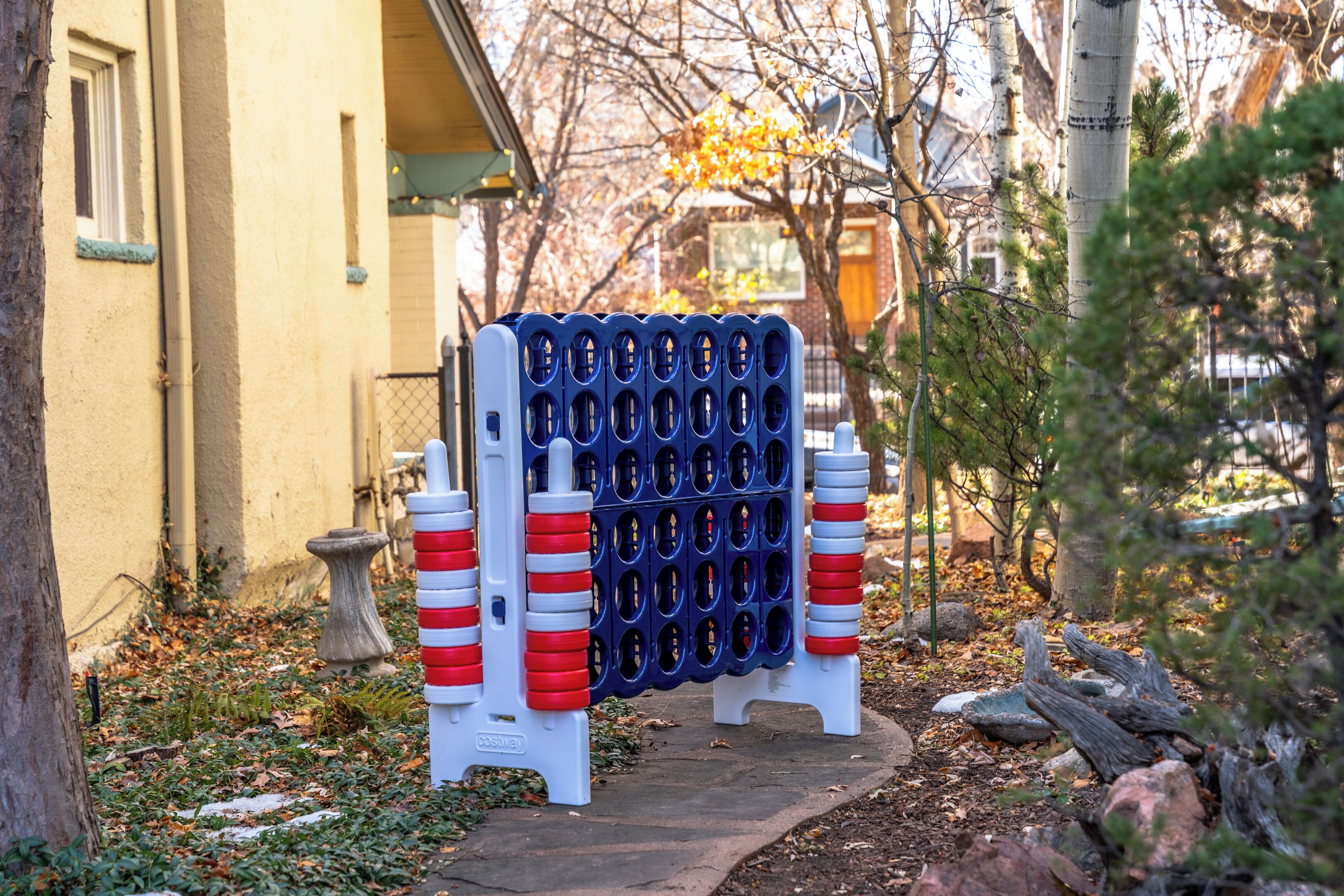 Una barrera azul y blanca con franjas rojas y blancas, un lavadero de piedra para pájaros y un sendero que lleva a un edificio.