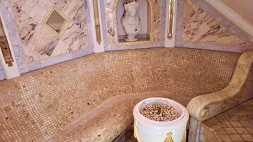 Una habitació amb una pica de mosaic, una paret amb dibuix de marbre i un bust decoratiu.
