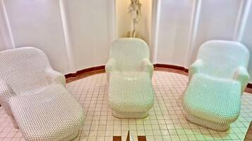A room with three chairs covered in a textured fabric, a geometric floor pattern, and a central decorative element.