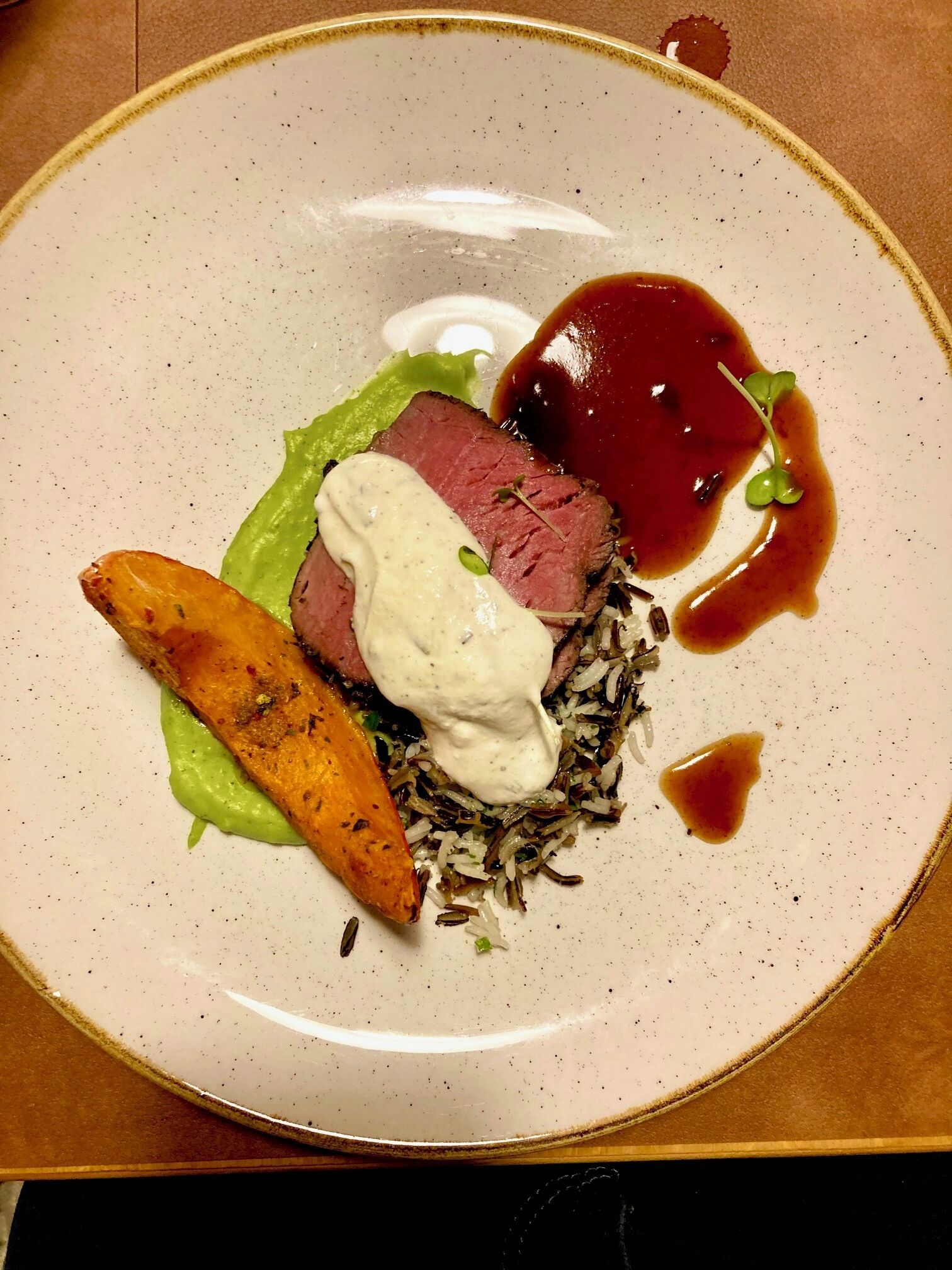 En tallerken med bøf, flødesauce, ris og en lille portion sauce.