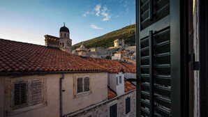 A view of a historic town with terracotta-tiled roofs, stone buildings, and a prominent church tower.