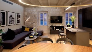 A modern living room with a stone wall, a sofa, a coffee table, and a TV mounted on the wall.