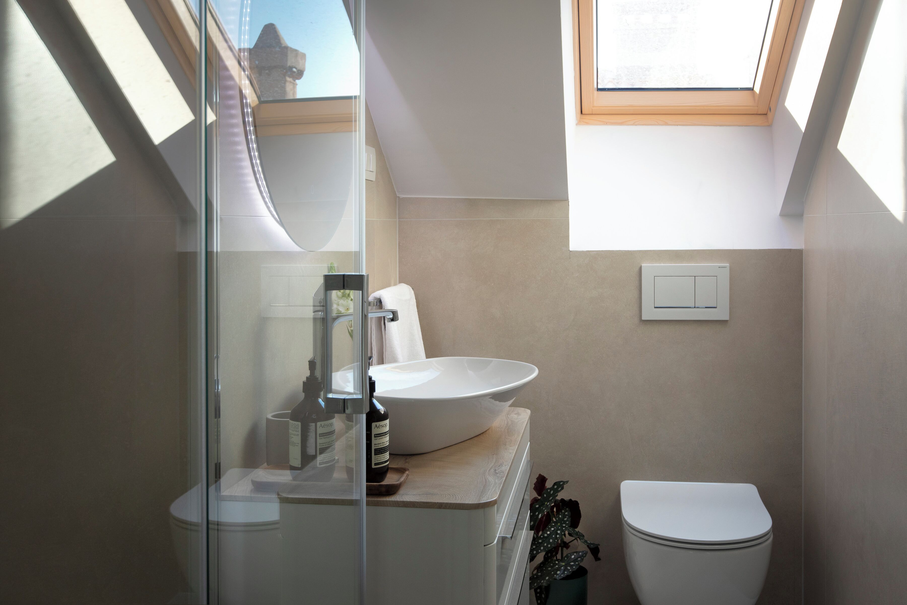 A modern bathroom with a skylight, a large white sink, and a toilet.