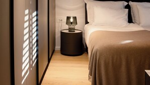 A bedroom with a bed, a bedside table, and a lamp.