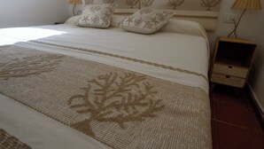 A neatly made bed with a patterned bedspread and two decorative pillows. There is a small wooden nightstand with a lamp beside the bed. - Blue Dawn - Holiday home with cozy terrace, garden & wonderful sea view. (Capo Coda Cavallo)